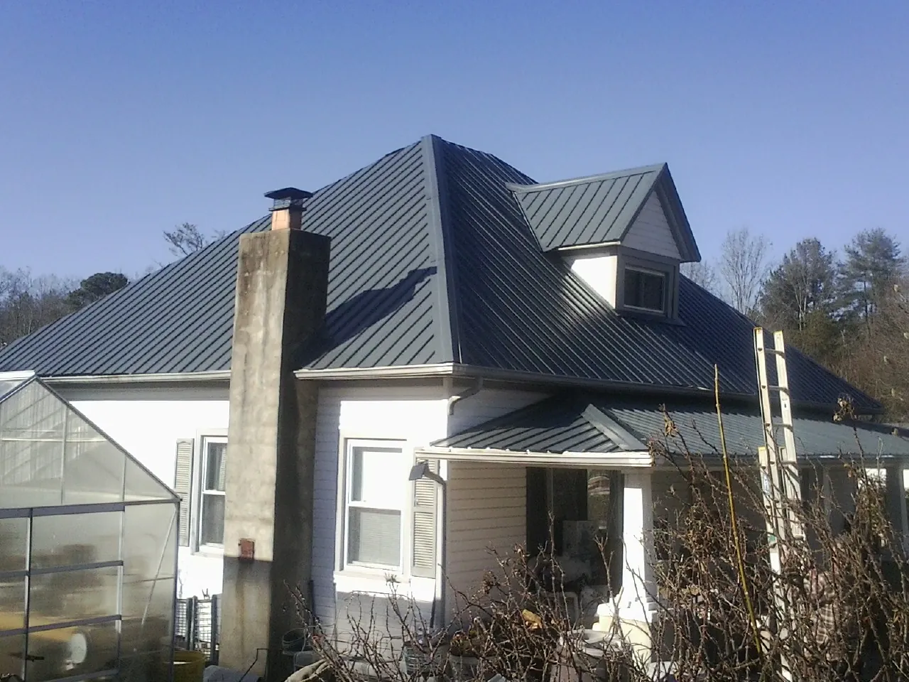 Dark blue standing seam metal roof on a white farmhouse with dormer — Slate & Tile Roof Repair by Roofing Brothers in New Preston Marble Dale