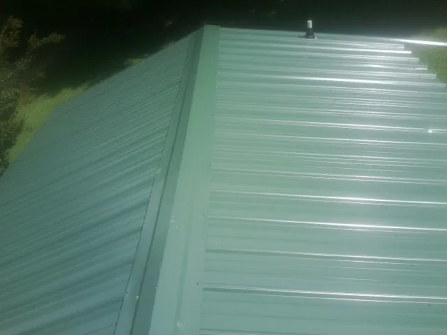 New green metal panels meeting at the ridge of a roof — Flat Roof Repair work by our crew in New Preston Marble Dale