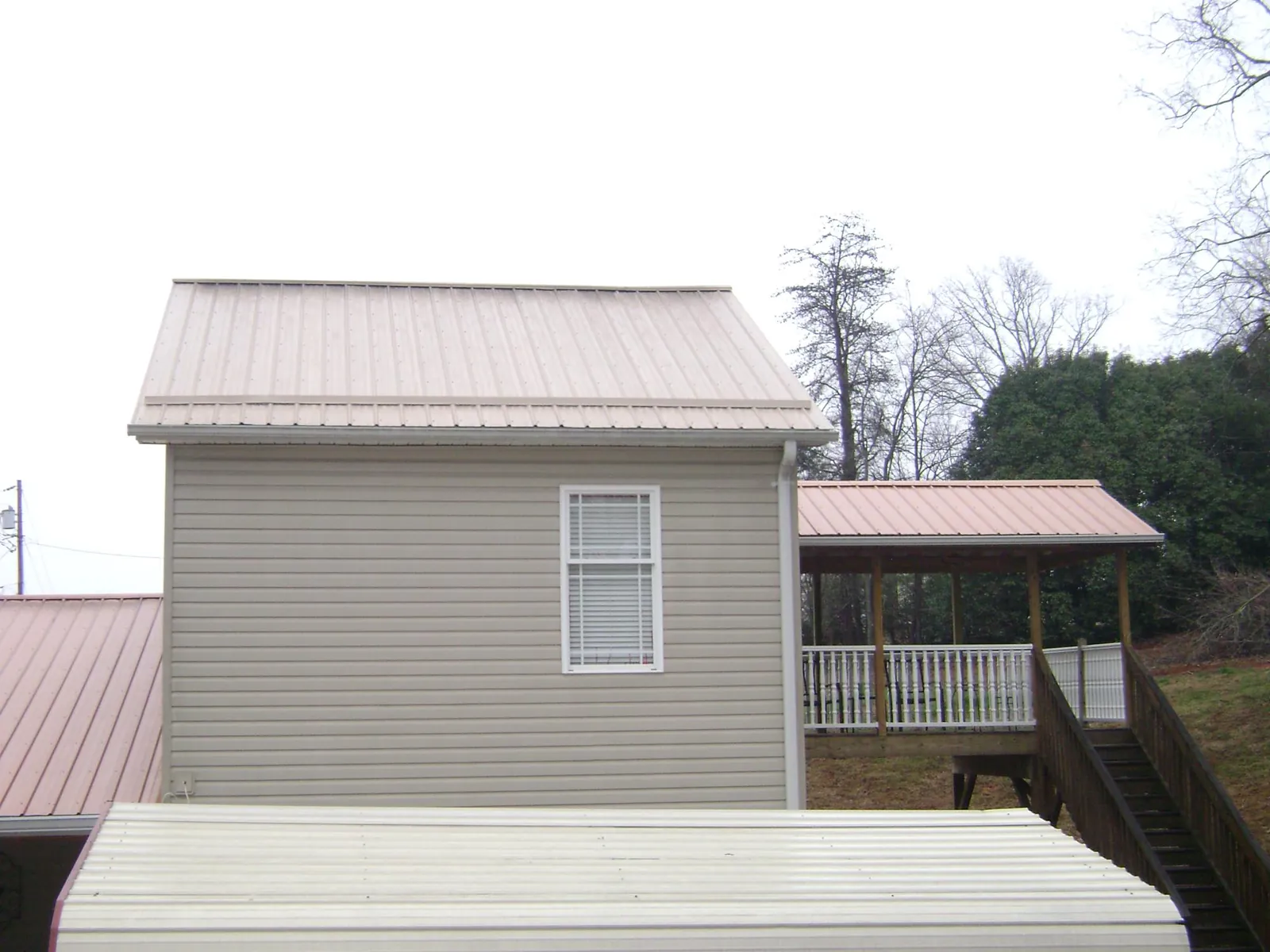 Tan metal roofs on a two story addition and attached porch, from a Roof Replacement job in New Preston Marble Dale